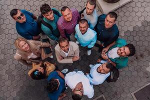 A top view photo of group of businessmen and colleagues standing together, looking towards the camera, symbolizing unity and teamwork.