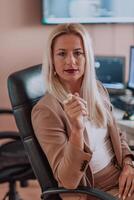 A businesswoman sitting in a programmer's office surrounded by computers, showing her expertise and dedication to technology. photo