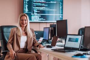 A businesswoman sitting in a programmer's office surrounded by computers, showing her expertise and dedication to technology. photo