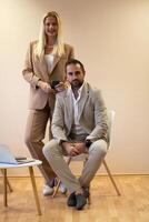 A business couple posing for a photograph together against a beige backdrop, capturing their professional partnership and creating a timeless image of unity and success. photo