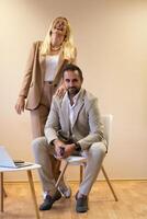 A business couple posing for a photograph together against a beige backdrop, capturing their professional partnership and creating a timeless image of unity and success. photo