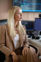 A businesswoman sitting in a programmer's office surrounded by computers photo