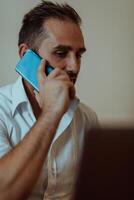 A businessman talking on his smartphone while seated in an office, showcasing his professional demeanor and active communication. photo