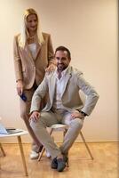 A business couple posing for a photograph together against a beige backdrop, capturing their professional partnership and creating a timeless image of unity and success. photo
