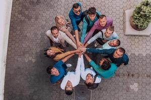 Top view photo of a group of business people and colleagues standing together holding hands, looking towards the camera, symbolizing unity and teamwork.
