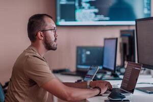 A programmer diligently testing smartphone applications while sitting in their office. photo