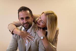 A business couple posing for a photograph together against a beige backdrop, capturing their professional partnership and creating a timeless image of unity and success. photo
