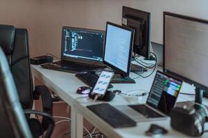 Computer screens running programming code in empty software developing agency office and computers parsing data algorithms in background. Neural network servers cloud computing in data room. photo