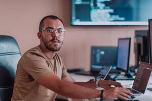 A programmer diligently testing smartphone applications while sitting in their office. photo