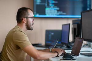 A programmer diligently testing smartphone applications while sitting in their office. photo