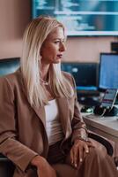 A businesswoman sitting in a programmer's office surrounded by computers, showing her expertise and dedication to technology. photo