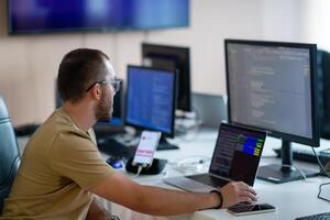 A programmer diligently testing smartphone applications while sitting in their office. photo