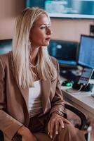 A businesswoman sitting in a programmer's office surrounded by computers, showing her expertise and dedication to technology. photo