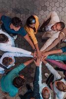 Top view photo of a group of business people and colleagues standing together holding hands, looking towards the camera, symbolizing unity and teamwork.