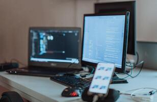 Computer screens running programming code in empty software developing agency office and computers parsing data algorithms in background. Neural network servers cloud computing in data room. photo