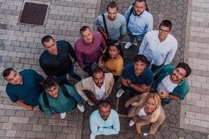 A top view photo of group of businessmen and colleagues standing together, looking towards the camera, symbolizing unity and teamwork.
