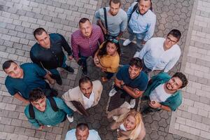 A top view photo of group of businessmen and colleagues standing together, looking towards the camera, symbolizing unity and teamwork.