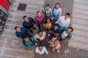 A top view photo of group of businessmen and colleagues standing together, looking towards the camera, symbolizing unity and teamwork.