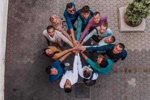 Top view photo of a group of business people and colleagues standing together holding hands, looking towards the camera, symbolizing unity and teamwork.