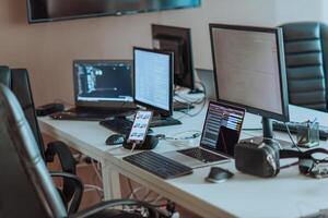 Computer screens running programming code in empty software developing agency office and computers parsing data algorithms in background. Neural network servers cloud computing in data room. photo