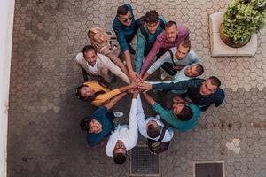 Top view photo of a group of business people and colleagues standing together holding hands, looking towards the camera, symbolizing unity and teamwork.