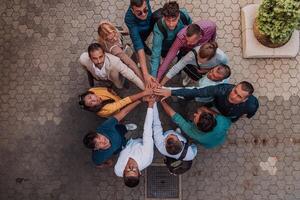 Top view photo of a group of business people and colleagues standing together holding hands, looking towards the camera, symbolizing unity and teamwork.