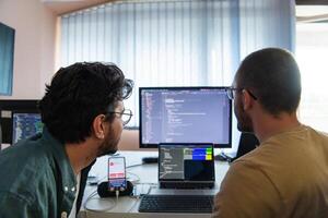 Programmers engrossed in deep collaboration, diligently working together to solve complex problems and develop innovative mobile applications with seamless functionality. photo