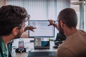 Programmers engrossed in deep collaboration, diligently working together to solve complex problems and develop innovative mobile applications with seamless functionality. photo