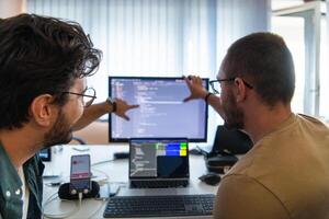 Programmers engrossed in deep collaboration, diligently working together to solve complex problems and develop innovative mobile applications with seamless functionality. photo