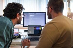 Programmers engrossed in deep collaboration, diligently working together to solve complex problems and develop innovative mobile applications with seamless functionality. photo