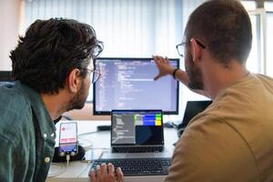 Programmers engrossed in deep collaboration, diligently working together to solve complex problems and develop innovative mobile applications with seamless functionality. photo