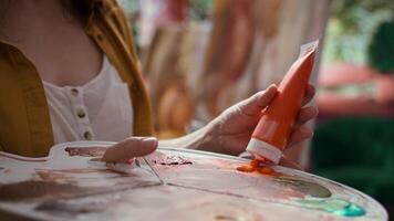 Woman with talent painting a rustic masterpiece and using fabric to clean her brush after changing the color. Artist feeling inspired to try a new painting technique in art and craft workshop. Camera B. video