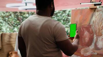Artist feeling inspired to paint a new artwork and holding phone with isolated display, thinking about painting technique in art and craft atelier. Working with motivation and creativity. Camera A. video