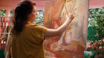 Artisan inspired by natural rural elements to paint a masterpiece on canvas, using modern paintbrushes in art studio. Working with motivation and creativity for fine art creative process. Camera B. video