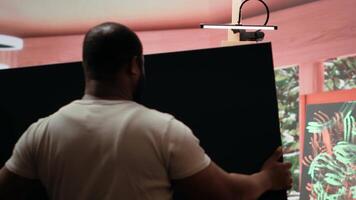 Artist is mixing different dye colors on a palette to create the perfect shade, creating a modern masterpiece on canvas. Male painter using creative tools and supplies for his artwork. Camera A. video