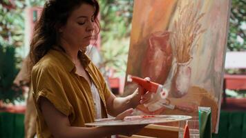 Painter spends quality time in her studio creating a masterpiece, perfecting latest fine art piece. Woman using pigments and painting techniques to highlight skill and dedication. Camera A. video
