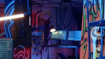 Software interface on computer screens showing developer code running in empty criminals den with graffiti sprayed on walls. Hacking malware programming in underground base video