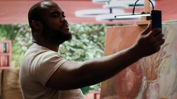African american painter recording a and self advertising masterpiece, using social media to promote art and create a branding as an influencer. Documenting artistic process. Camera A. video