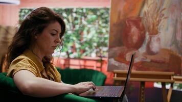 Artist doing research to find contemporary inspiration for a new painting creation, searching for her muse or a rustic model. Woman browsing the internet for creativity and motivation. Camera B. video