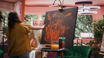 Confident artist stands before an easel and painting with her fingers, innovative finger paint and handprint technique for creating a beautiful artwork with watercolor paints. Rustic art. Camera B. video
