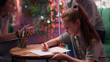 Therapist guiding a troubled teen through creative therapy system, using drawing as a method to manage intrusive thoughts and mental health. The mother observes, offering emotional support. Camera A. video
