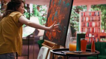 Team of artists in a gallery atelier working on a new art piece, using finger painting technique for abstract creation. Blending acrylic paints with precision to create modern design. Camera A. video