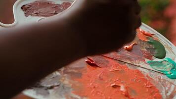 Talented artist using modern tools and painting supplies to create an artwork, mixing watercolors on a palette during his creative process. Man working on a masterpiece. Close up. Camera A. video