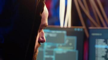 Malicious man hacking, stealing credit card numbers and manipulating banking systems for his own personal gain. Extreme close up of rogue programmer running code in graffiti painted basement, camera B video