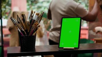 In a creative atelier, painters use colorful paint tubes and brushes to create a masterpiece next to copy space display. Team of artists working on a nature inspired painting. Camera A. video