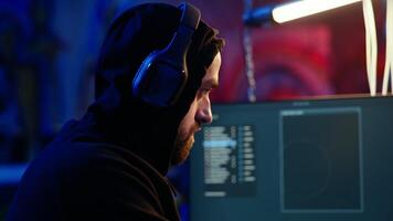 Hacker hiding in bunker removing headphones to hear suspicious sounds, feeling anxious after stealing data from victims. Man stopping music, scared about being caught by police, camera A close up video