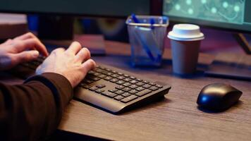 Meticulous hacker typing on computer keyboard, doing data breaches and financial theft in dark bunker. Close up shot on cybercriminal stealing users bank account credentials, camera B video