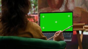 Talented woman artist focuses on her painting and chroma key screen, creating masterpiece with palette of vibrant colors. Showcasing her creativity and dedication to fine art paintwork. Camera A. video