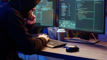 Hacker hiding in underground bunker, chatting with friend in telephone call, anxious after stealing data from victims using computer virus, scared about being caught by police, camera B close up video