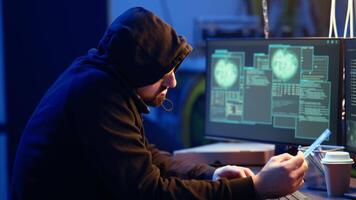 Hacker in abandoned warehouse talking on phone with partner, stealing data after using phishing technique. Man in telephone call with colleague, tricking users into revealing information, camera A video